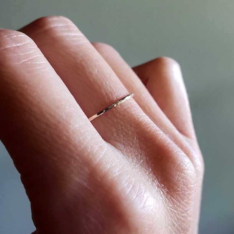 Pu&ograve; includere: Un sottile anello a fascia d'oro con una texture martellata.