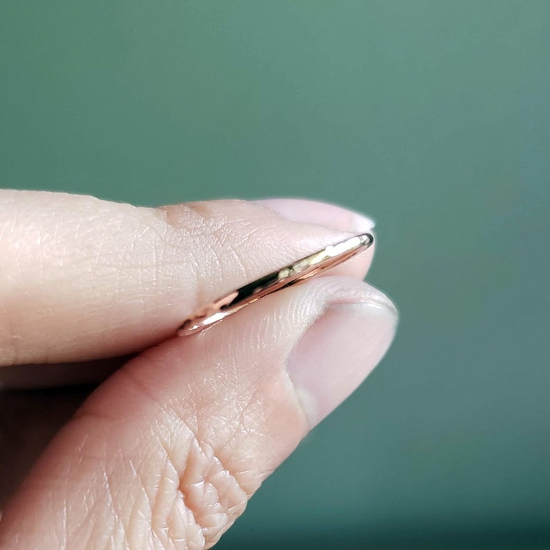 May include: A thin, rose gold band ring.
