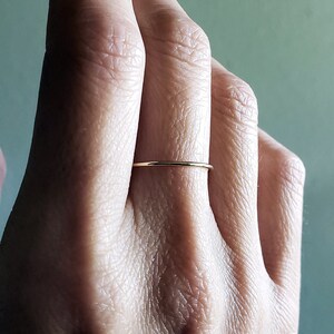 Pu&ograve; includere: Un anello sottile in oro indossato su un dito.