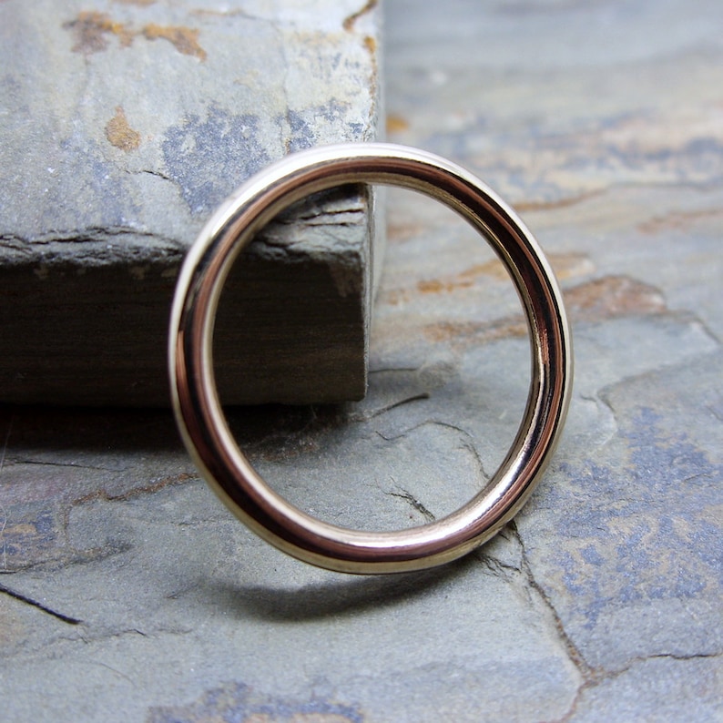 May include: A smooth, gold-colored metal ring with a round shape.