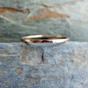 May include: A thin, hammered, rose gold band ring.