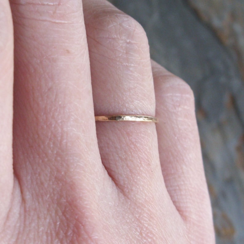 Pu&ograve; includere: Un anello sottile in oro con una texture martellata.
