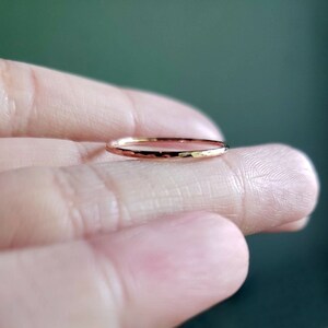 May include: A thin, hammered rose gold band ring.