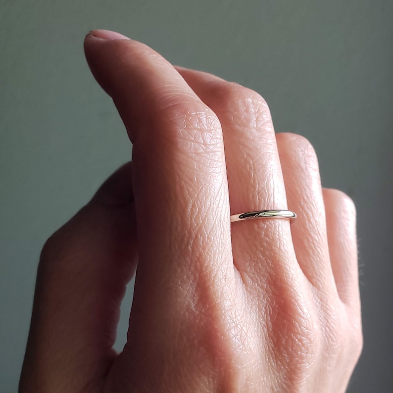 May include: A simple gold band ring worn on a finger.