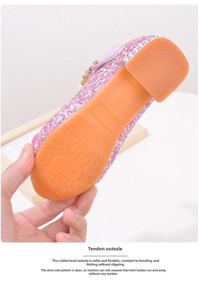 Puede incluir: Zapato rosa brillante para ni&ntilde;os con un tac&oacute;n peque&ntilde;o y una suela de goma. La suela es naranja y presenta un dise&ntilde;o de personaje de dibujos animados. El zapato tiene una hebilla y un detalle de lazo. El texto en la imagen dice "Tendon outsole".