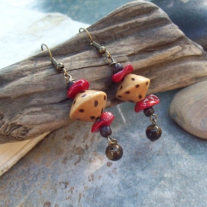 May include: A pair of dangle earrings with brown and black ceramic dice-shaped beads, red coral beads, and brown tiger's eye beads.