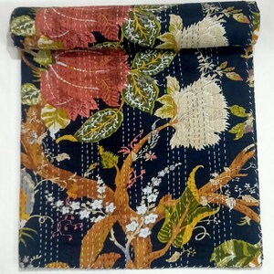 May include: A folded rectangular quilt featuring a dark navy blue background with a large-scale floral pattern. The design includes oversized red and white flowers, green leaves, and brown branches, all accented by visible white running stitch quilting.