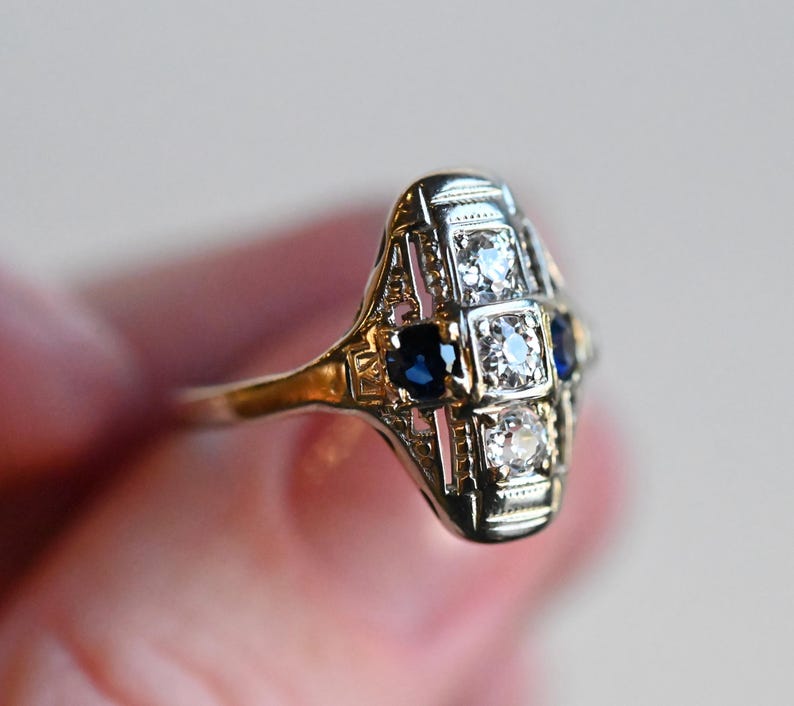 May include: A silver ring with a geometric design featuring blue sapphires and clear diamonds.