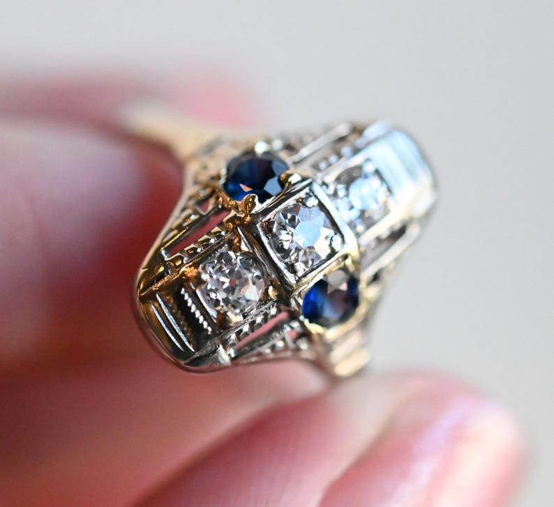 May include: A vintage ring with a geometric design featuring four blue sapphires and four clear diamonds set in a gold and silver band.