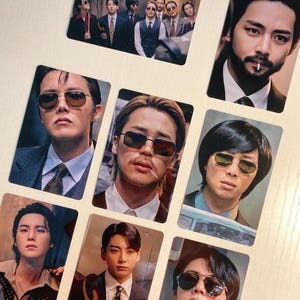May include: A collection of rectangular photo cards featuring portraits of men in suits and sunglasses. The cards showcase various individuals, with some cards displaying multiple people. The overall aesthetic is vintage-inspired.