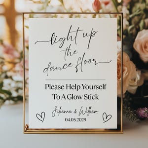 Puede incluir: Un letrero con marco dorado con el texto "light up the dance floor" y "Please Help Yourself To A Glow Stick". El letrero también incluye los nombres "Julianna & William" y la fecha "04.05.2029".