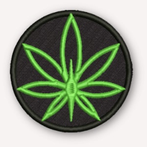 May include: A circular embroidered patch featuring a bright lime green leaf design centered on a solid black background. The patch has a thick, stitched black border that frames the vibrant green botanical graphic, creating a high-contrast look.