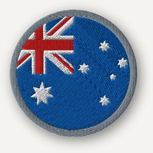 Puede incluir: Un parche bordado circular con el diseño de la bandera de Australia. El parche tiene un fondo azul con la Union Jack en la esquina superior izquierda, una estrella grande de siete puntas debajo y cinco estrellas blancas más pequeñas a la derecha.