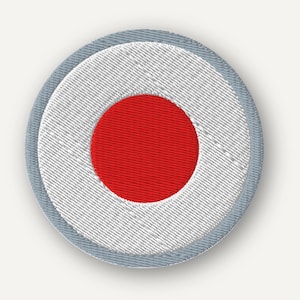 May include: A circular embroidered patch featuring a solid red center circle surrounded by a wide white ring and a thin light gray border. The embroidery shows a distinct diagonal stitch pattern throughout the white and red sections of the design.