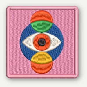 以下が含まれることがあります： 薄いピンク色の布地を背景にした正方形の刺繍ワッペン。中央の青い円の中に、オレンジ色の虹彩と黒い瞳孔を持つ白い目が描かれており、その上下をオレンジ、緑、黄色の半円形の図形が囲んでいるデザイン。