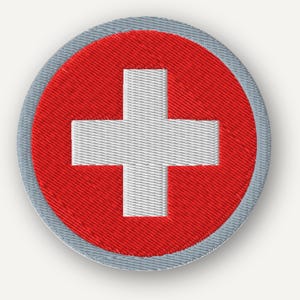May include: A circular embroidered patch featuring a vibrant red background with a centered white cross. The design is enclosed by a thin, light gray stitched border that defines the circular shape of the emblem against the plain background.