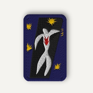 May include: A rectangular embroidered patch with a dark blue border. The center features a black diagonal band containing a white stylized bird figure with a red heart-shaped detail. Several small yellow star-like shapes surround the bird.