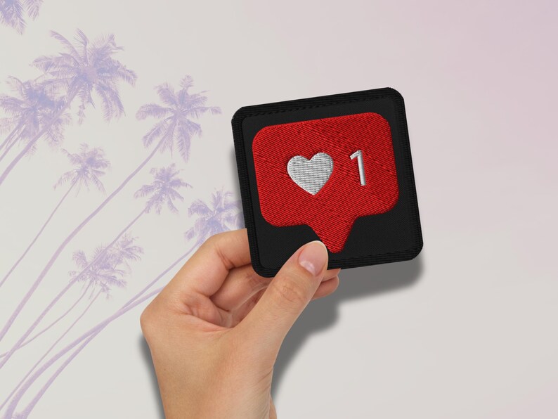 Flat lay of Micro Influencer patch iron-on with red Instagram heart icon, 1 Like text, on neutral background, showing crisp embroidery and playful self-deprecating humor, perfect for jackets, backpacks, or gifts.