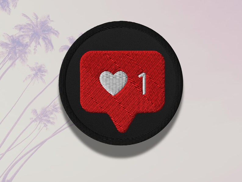 Flat lay of Micro Influencer patch iron-on with red Instagram heart icon, 1 Like text, on neutral background, showing crisp embroidery and playful self-deprecating humor, perfect for jackets, backpacks, or gifts.