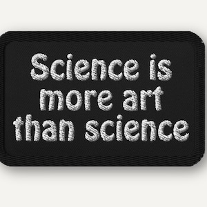 May include: Black rectangular patch with white embroidered text that reads "Science is more art than science". The patch has a black border and is likely an iron-on or sew-on patch.