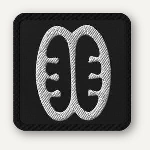 May include: Black square patch with a white embroidered Adinkra symbol, a visual representation of concepts or proverbs. The symbol is a stylized design with rounded shapes and a central vertical line. The patch has a black border.