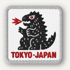 May include: Embroidered patch featuring a black dinosaur-like creature with red eyes and a red flame. The text "TOKYO-JAPAN" is in red at the bottom. The patch has a white background and a gray border.