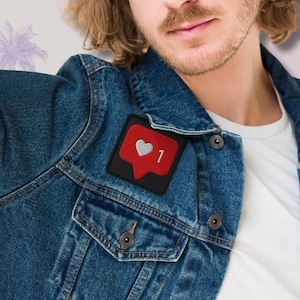 Flat lay of Micro Influencer patch iron-on with red Instagram heart icon, 1 Like text, on neutral background, showing crisp embroidery and playful self-deprecating humor, perfect for jackets, backpacks, or gifts.