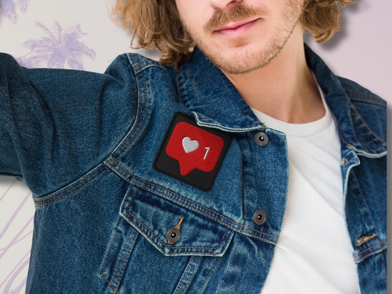 Flat lay of Micro Influencer patch iron-on with red Instagram heart icon, 1 Like text, on neutral background, showing crisp embroidery and playful self-deprecating humor, perfect for jackets, backpacks, or gifts.