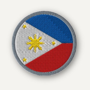 May include: A circular embroidered patch featuring the flag of the Philippines. The design includes a white triangle on the left with a central yellow sun and three yellow stars, alongside horizontal blue and red bands, all bordered by grey.