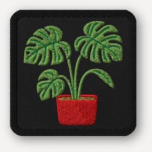 May include: Embroidered patch showing a green Monstera plant in a red pot on a black background. The plant has large, split leaves. The patch has a black border and is square-shaped.