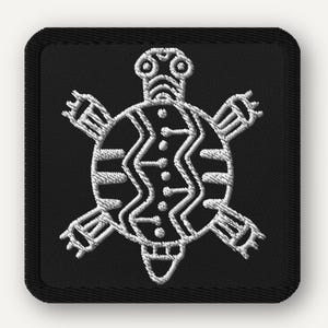 Puede incluir: Parche cuadrado negro con un diseño de tortuga bordada en blanco. La tortuga tiene un patrón detallado y estilizado en su caparazón y extremidades. El parche tiene un borde negro y probablemente sea un parche para planchar o coser.