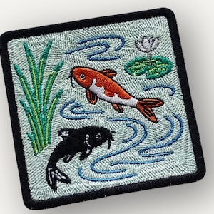 May include: Embroidered patch featuring two koi fish swimming in a pond. The patch has a square shape with rounded corners and a black border. The fish are orange and black, with blue water and green plants.