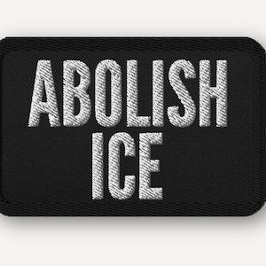 May include: A black rectangular patch with white embroidered text that reads "ABOLISH ICE". The patch has a black border and is set against a white background. The text is in a bold, sans-serif font.