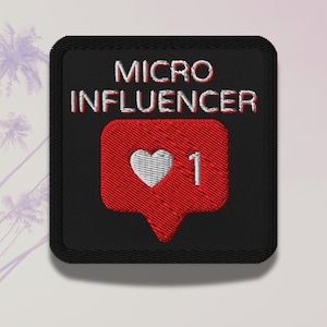 Puede incluir: Parche cuadrado negro bordado con las palabras "MICRO INFLUENCER" en blanco y rojo. Una burbuja de diálogo roja con un corazón blanco y el número 1 está debajo del texto. El parche tiene un borde negro.