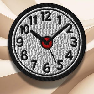 Pode incluir: Patch bordado com um mostrador de relógio com algarismos e ponteiros pretos sobre um fundo cinza claro. O relógio tem um centro vermelho e uma borda preta. Os ponteiros apontam para aproximadamente 10h10.