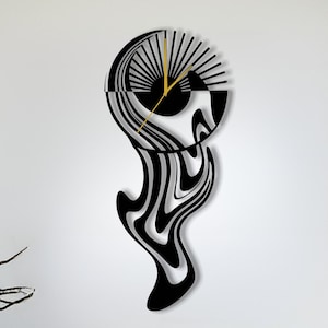 May include: A modern, abstract wall clock with a black and white wavy design. The clock face is a semi-circle with gold-colored hands and radial lines. The clock is mounted on a white wall, with orange and teal cushions below.