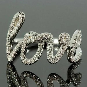May include: A silver ring with the word "love" spelled out in diamonds.