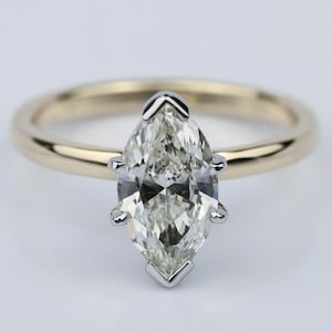 May include: A gold band engagement ring with a marquise cut diamond.