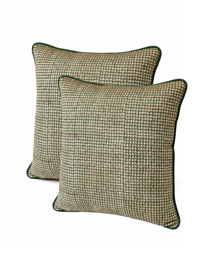 May include: Two decorative throw pillows with a green and white dot pattern. The pillows have a green border and are rectangular and square shaped. The pillows are on a white background.