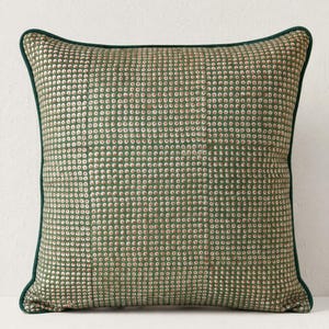 May include: Square decorative pillow with a green background and a pattern of small, evenly spaced white and red dots. The pillow has a dark green border.