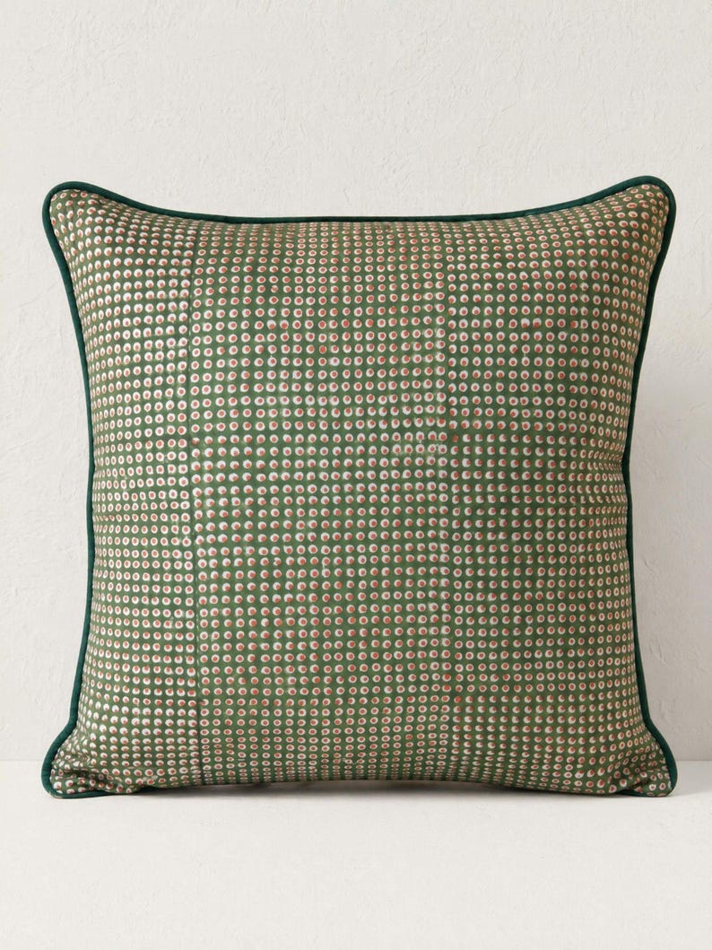 May include: Square decorative pillow with a green background and a pattern of small, evenly spaced white and red dots. The pillow has a dark green border.
