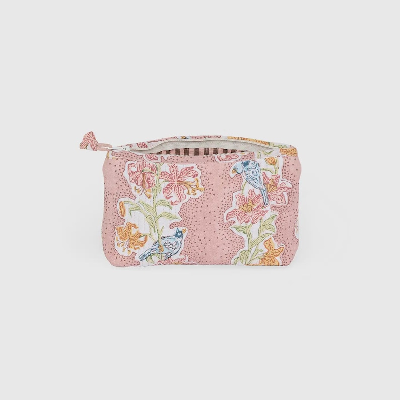 May include: A pink floral patterned zippered pouch with a bird and flower design. The pouch features a repeating pattern of pink flowers, green leaves, and blue birds. The zipper pull is a small fabric loop.