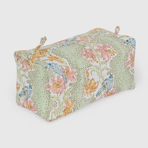 May include: A rectangular, floral-patterned storage box. The box features a light green background with a repeating pattern of pink, orange, and yellow flowers, along with blue birds. Two small fabric loops are attached to the top.