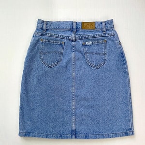 May include: Light blue denim skirt with two back pockets and a small Lee label. The skirt has a classic, casual style, perfect for everyday wear. The skirt is made of a durable denim material.