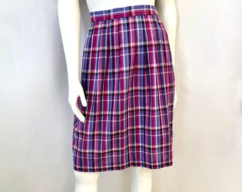 May include: A knee-length plaid skirt in shades of purple, pink, and white. The skirt features a classic plaid pattern with vertical and horizontal lines. The skirt is displayed on a mannequin, showcasing its pleated design and tailored fit.