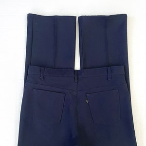 May include: Navy blue trousers with a classic design. The trousers feature two back pockets and a button and zip closure. The trousers are made of a smooth fabric and have a straight leg cut.