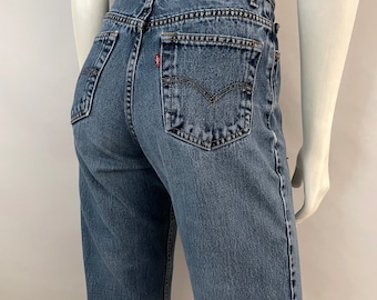 May include: Blue denim jeans with a high waist and a classic five-pocket design. The jeans feature a Levi Strauss & Co. label on the back and a small red tag on the back pocket. The jeans are a medium wash.
