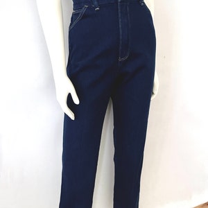 K&ouml;nnte beinhalten: Dunkelblaue Jeans mit hoher Taille und geradem Bein. Die Jeans hat einen Knopf- und Rei&szlig;verschluss und sichtbare N&auml;hte in einer hellen Farbe. Die Jeans wird auf einer Schaufensterpuppe pr&auml;sentiert.