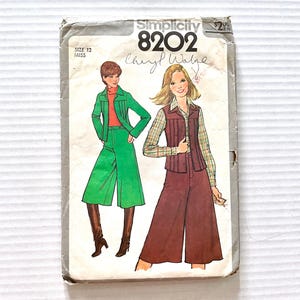 May include: Vintage Simplicity 8202 sewing pattern featuring illustrations of a woman in a green pantsuit and a woman in a brown pantsuit with a vest. The pattern is size 12 Misses. The pattern is signed "Cheryl Walge".