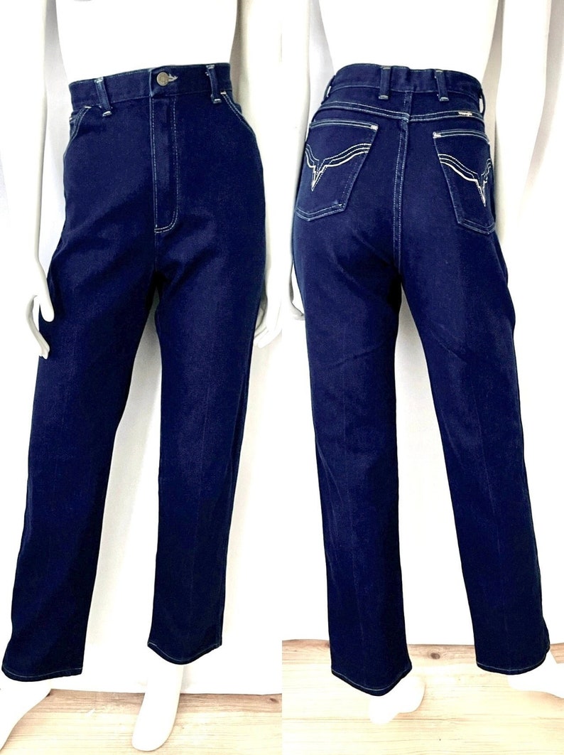 K&ouml;nnte beinhalten: Dunkelblaue Jeans aus Denim mit hohem Bund und geradem Bein. Die Jeans hat wei&szlig;e N&auml;hte und dekorative N&auml;hte auf den Ges&auml;&szlig;taschen. Die Jeans wird auf einer Schaufensterpuppe pr&auml;sentiert.